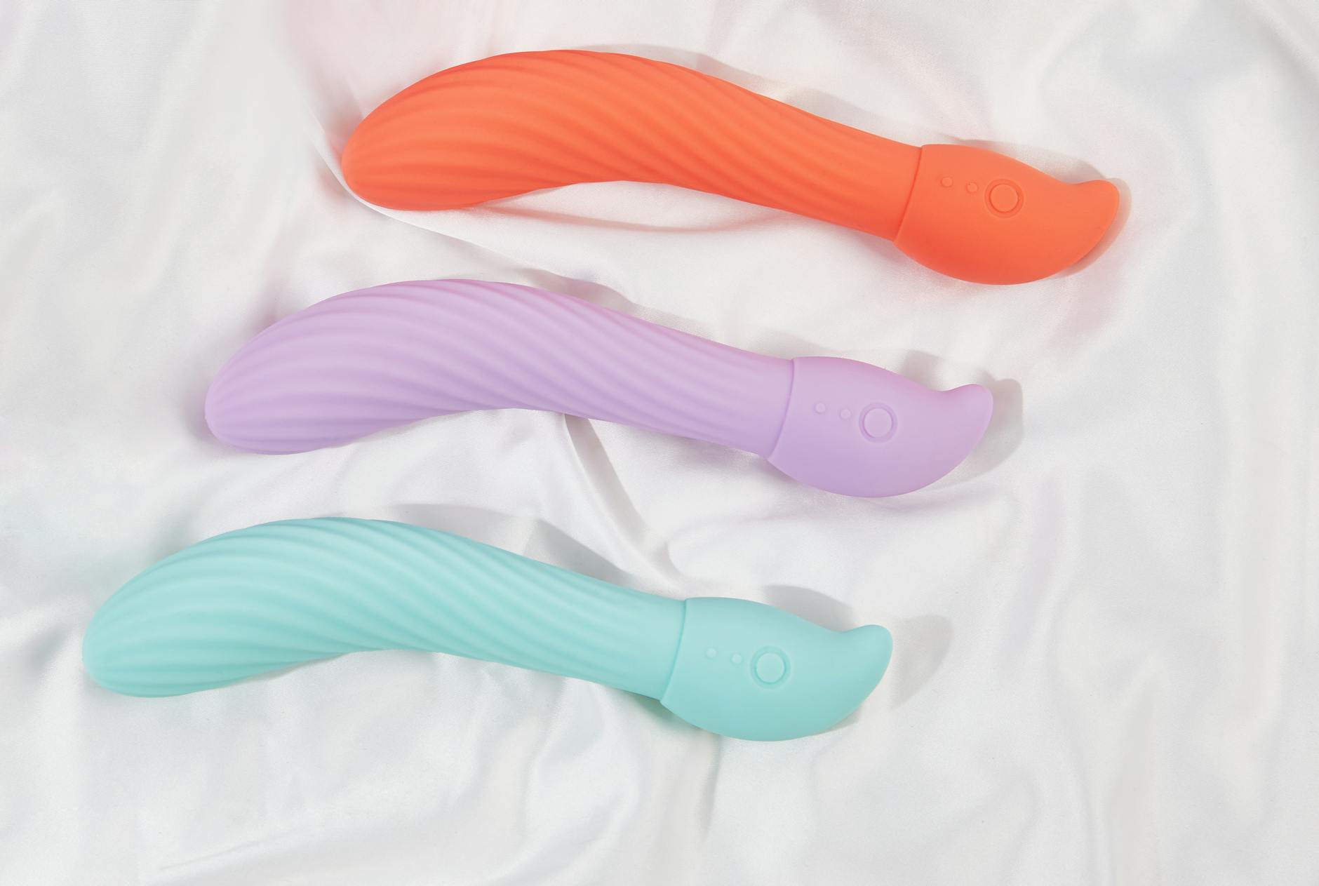 Blue silicone clitoral vibrator held in hand against purple background, symbolizing self-care and sexual wellness