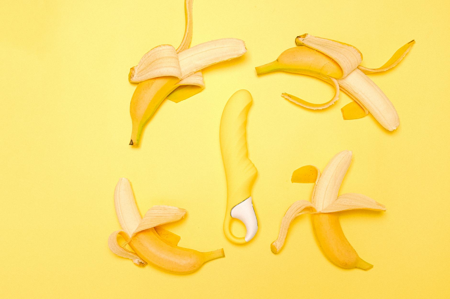 Yellow lemon vibrator arranged with fresh lemons on a yellow background.