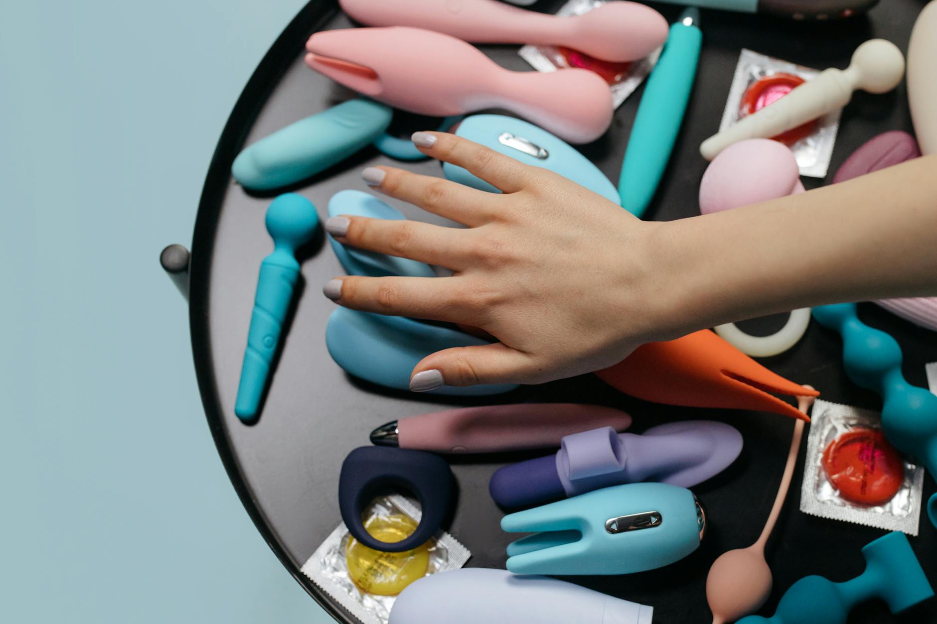 A hand holding a vibrator against a purple backdrop, representing reconnecting with sensation.