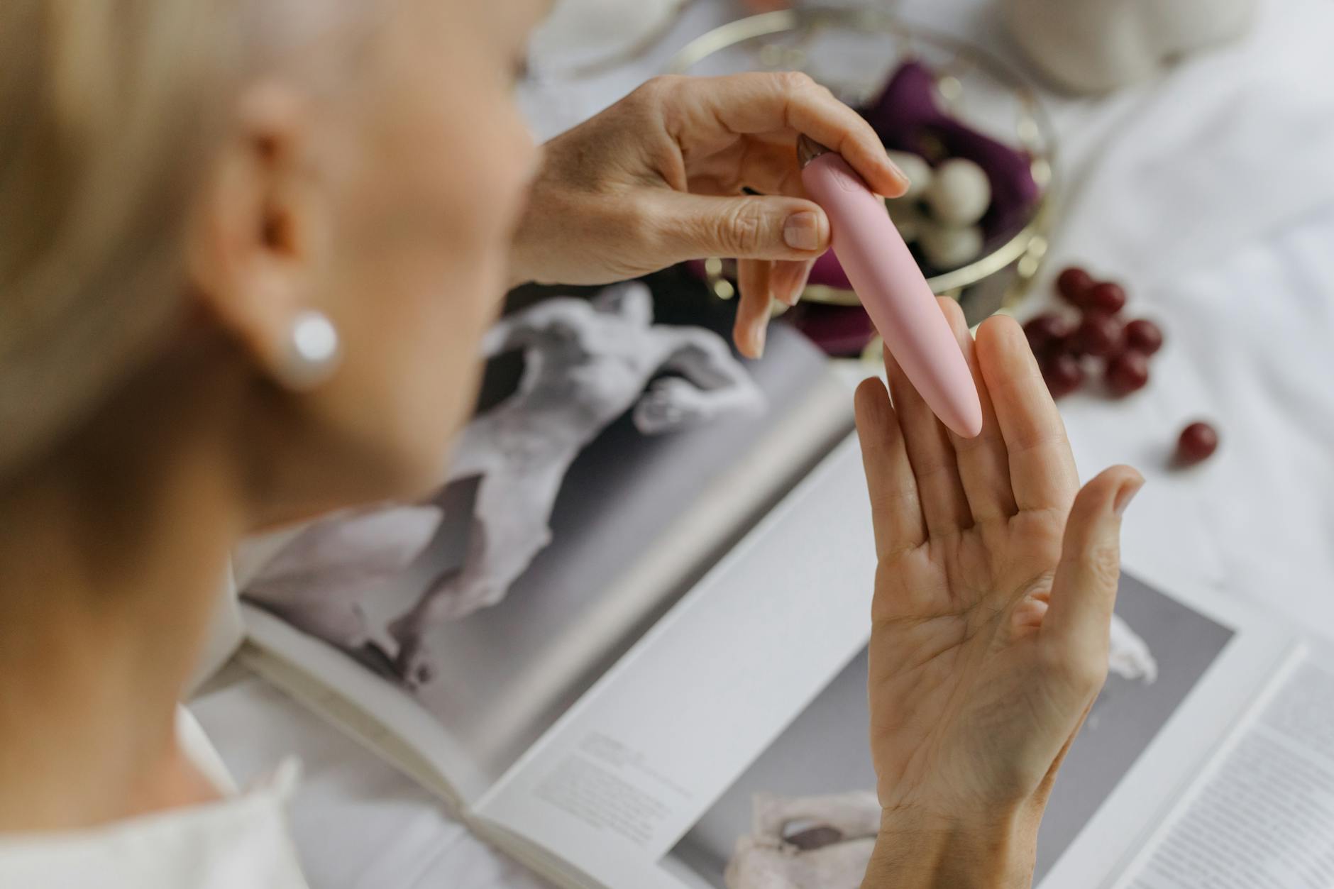 Close-up of hands holding a pink vibrator, representing intimate reconnection and self-care.