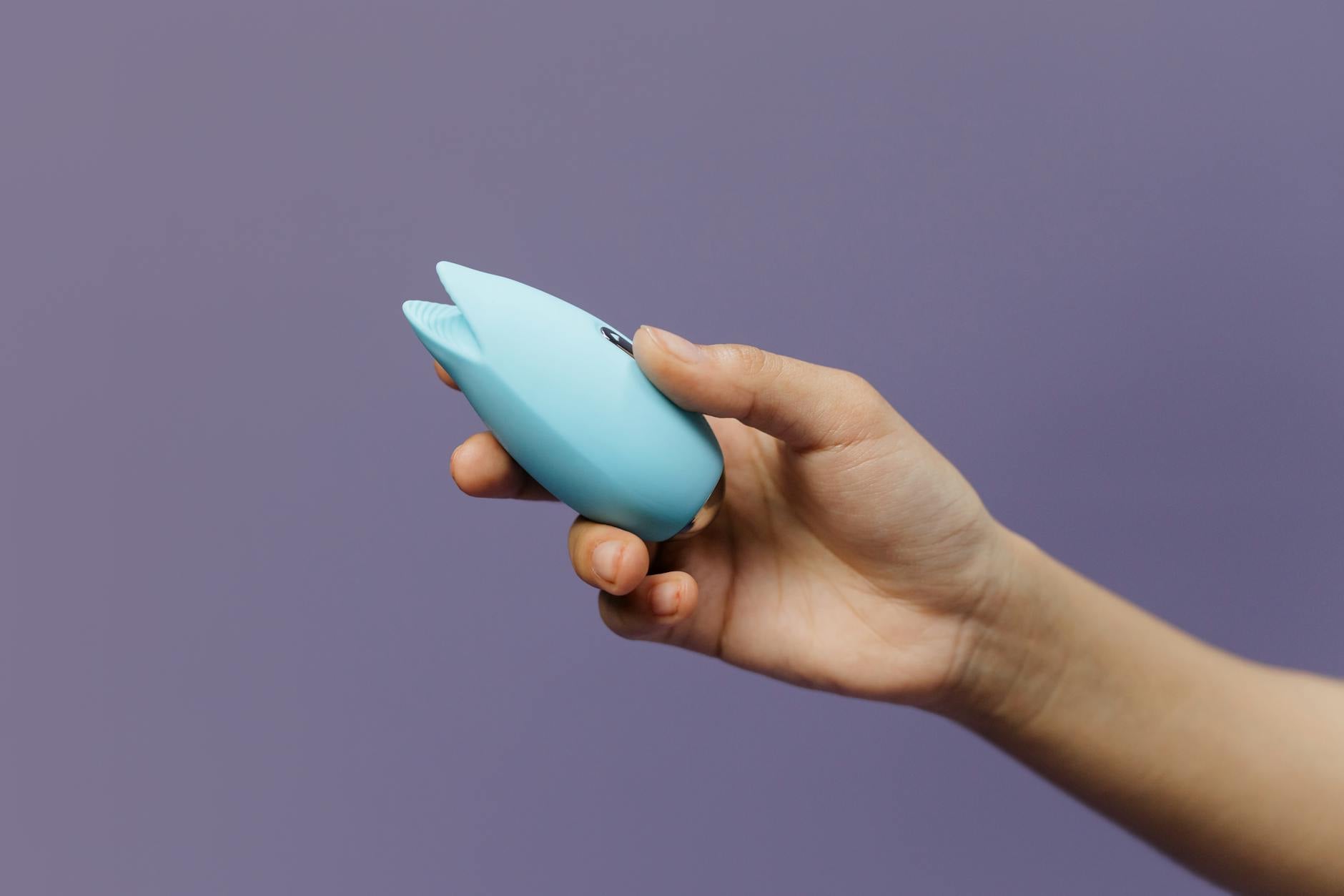 A blue vibrator surrounded by flowers and citrus on a bright background, symbolizing sexual wellness and renewed intimacy.
