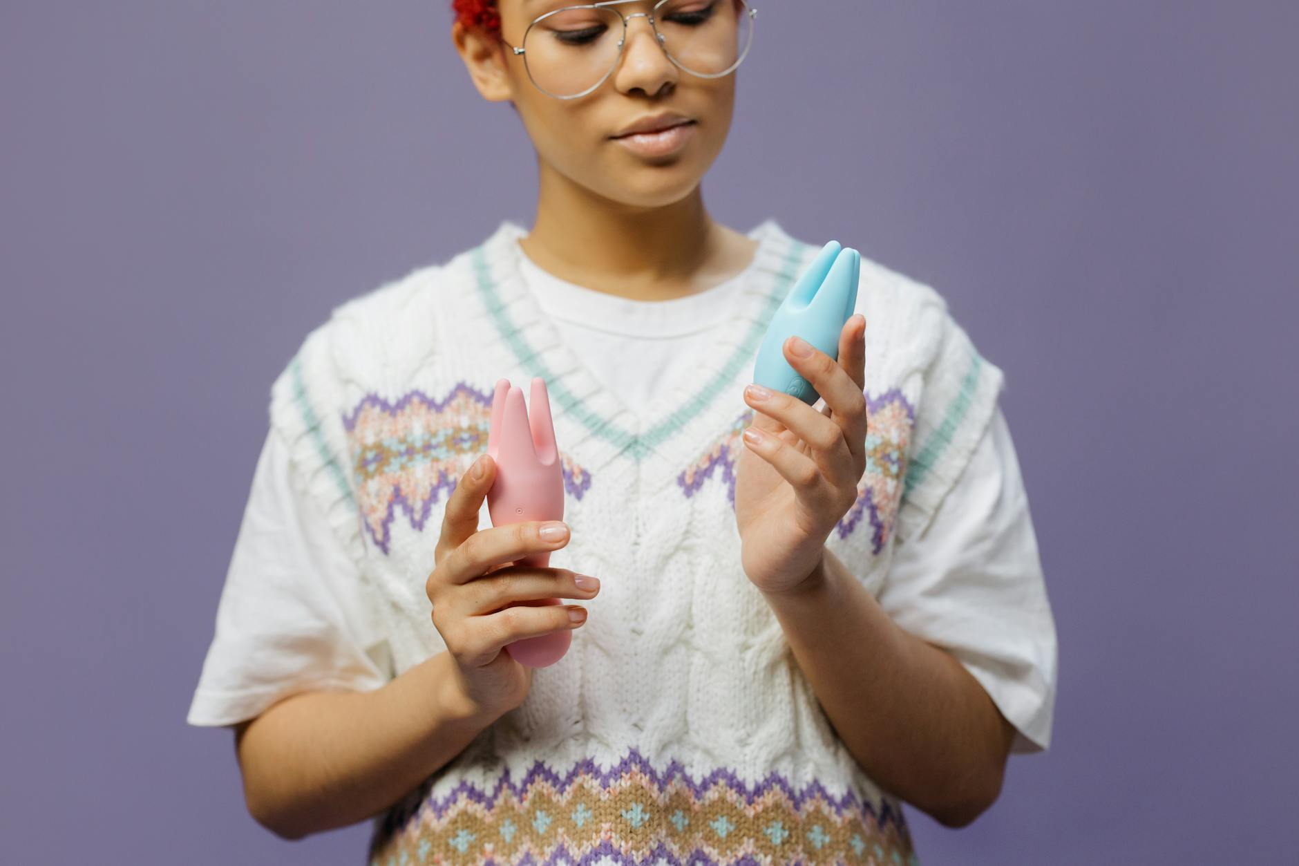 Woman holding colorful vibrators in contemplative pose, representing the nuanced experience of orgasm variability.